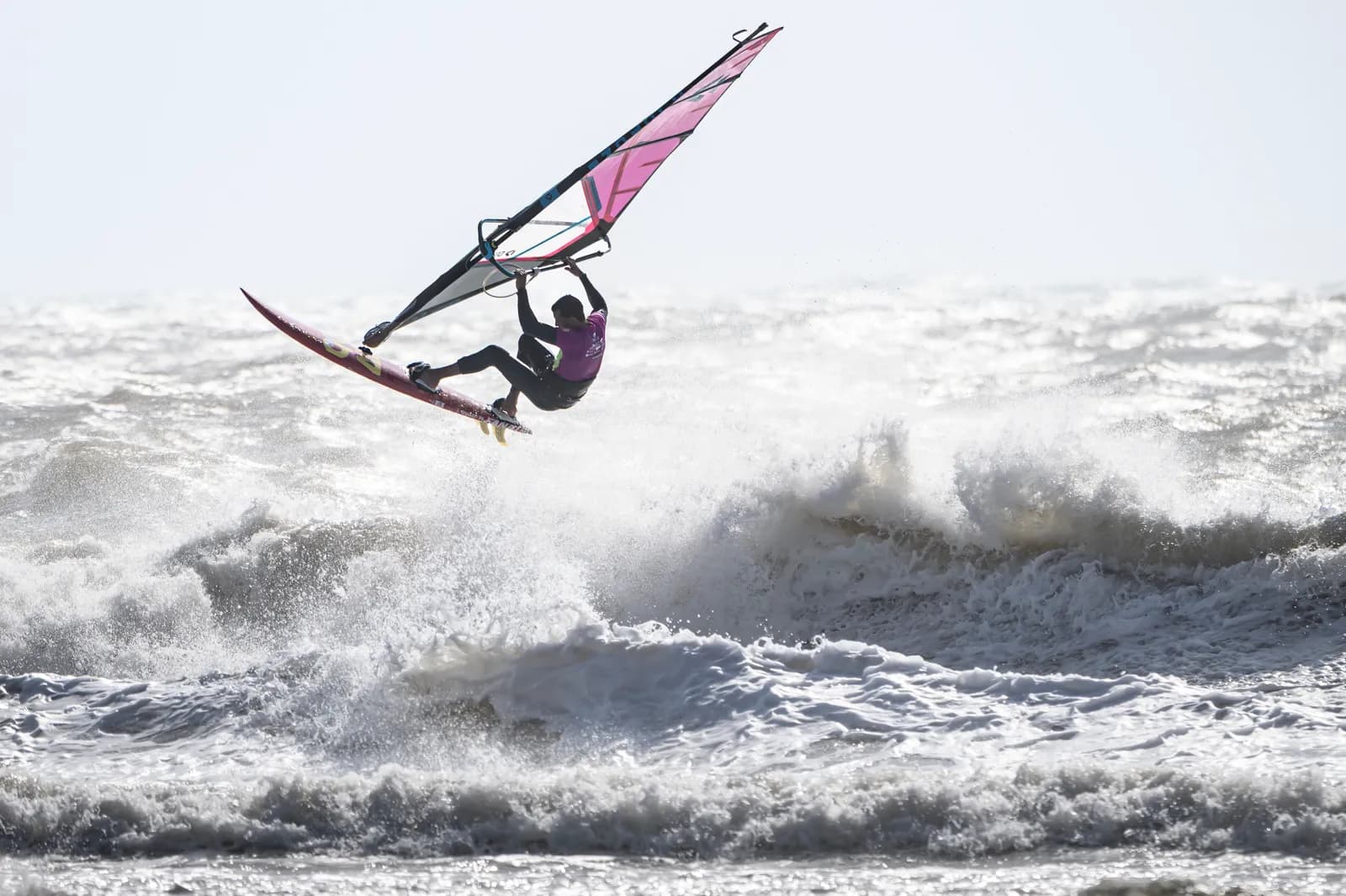 Rider con vela rosa despegando de una ola rompiente en Moulay Bouzerktoune