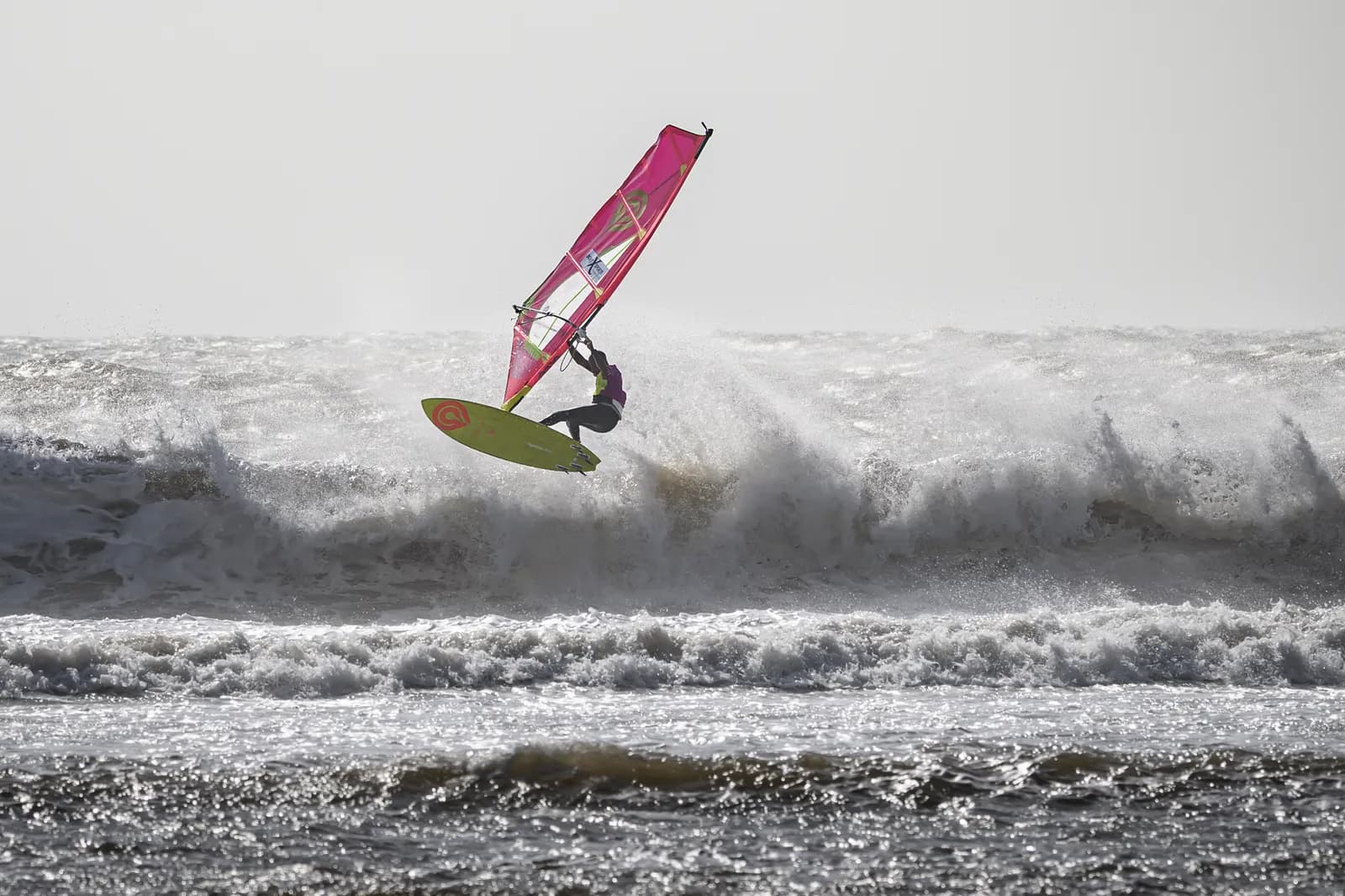 Windsurfer mit pinkem Segel an einer brechenden Welle in Moulay Bouzerktoune